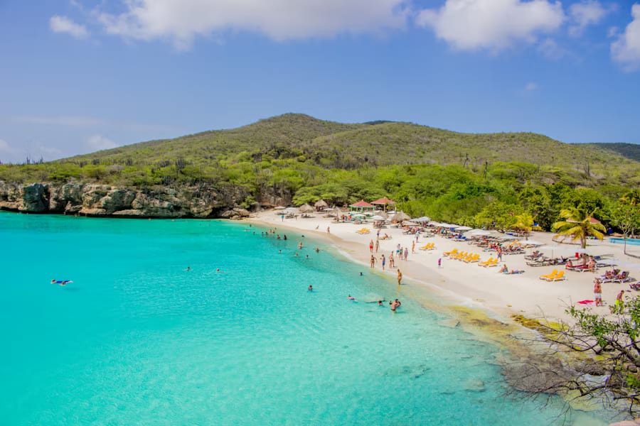 Wit zandstrand op Curaçao met turquoise zee en rotsige kustlijn
